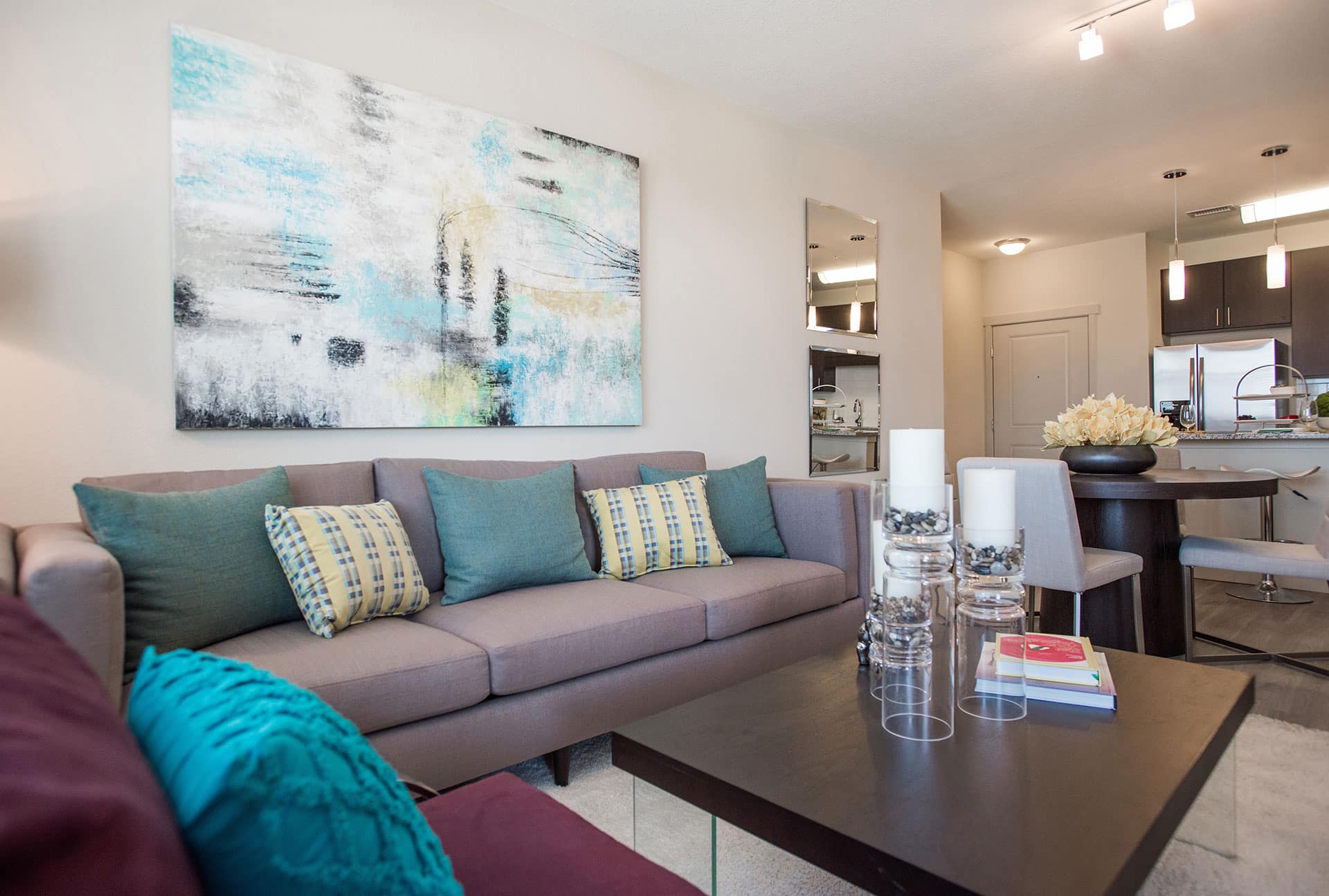 Gray couch with teal and yellow accent pillows, espresso coffee table.