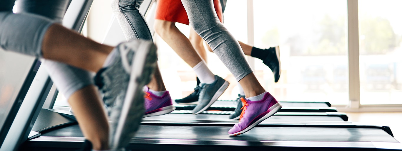 Photo of peoples legs and feet running on a several treadmills