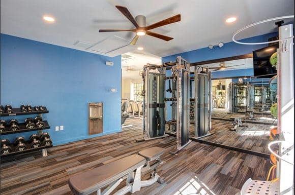 Gym with mirrors and fitness machines and ceiling fan