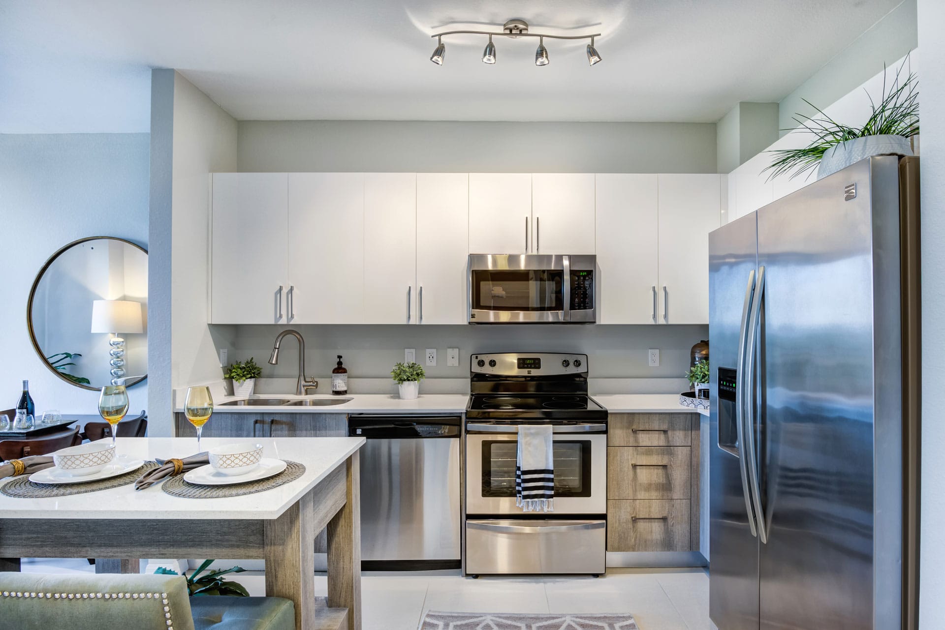 Modern kitchen with island stainless appliances, white cabinets.