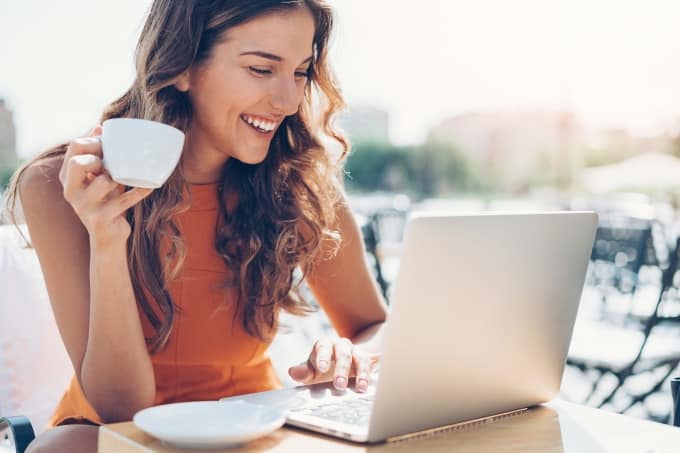 Pretty young woman drinking coffee on a laptop.