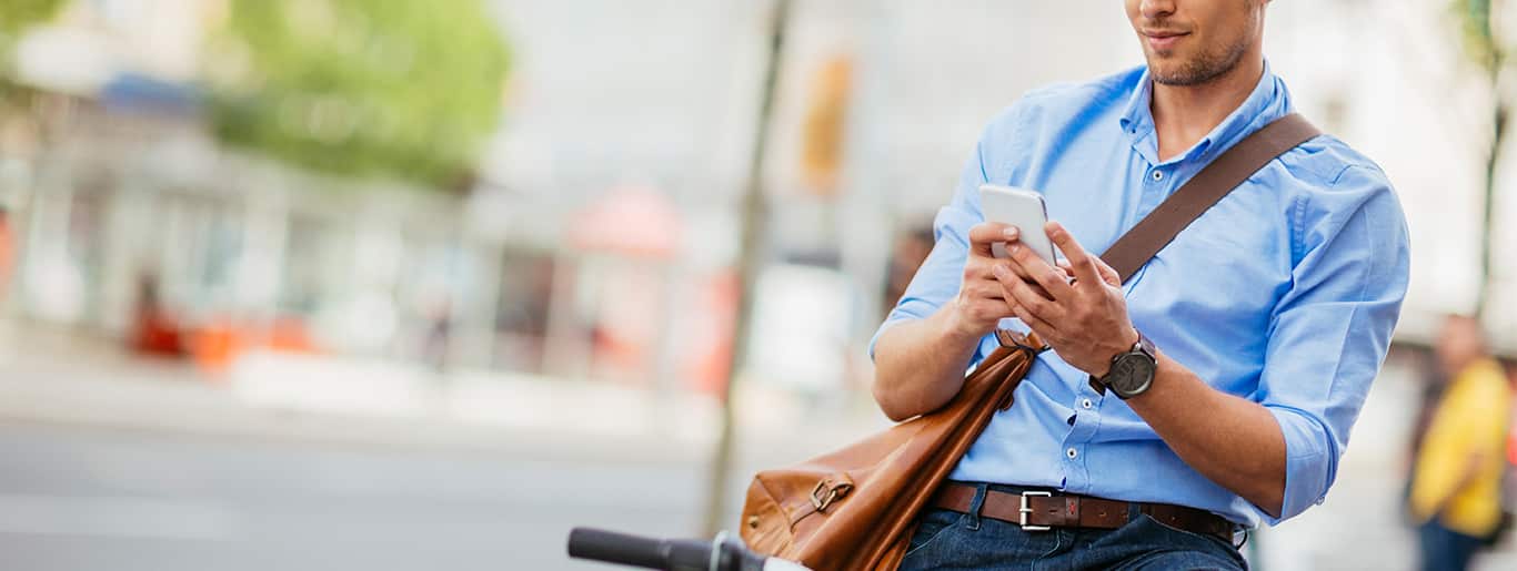 Young man sitting on a bike, texting on cell phone.